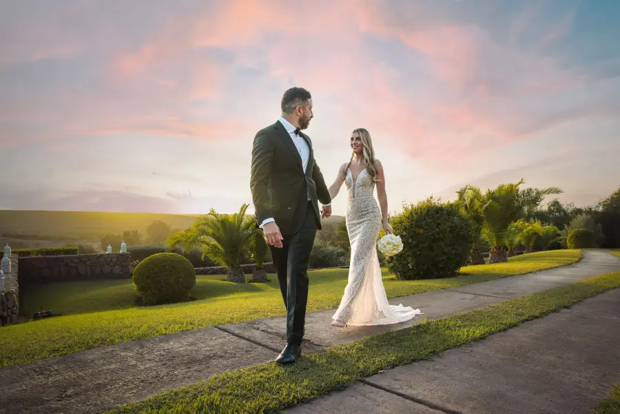 Couple walking hand in hand under a pink sunset sky - wedding photographer Marrakech