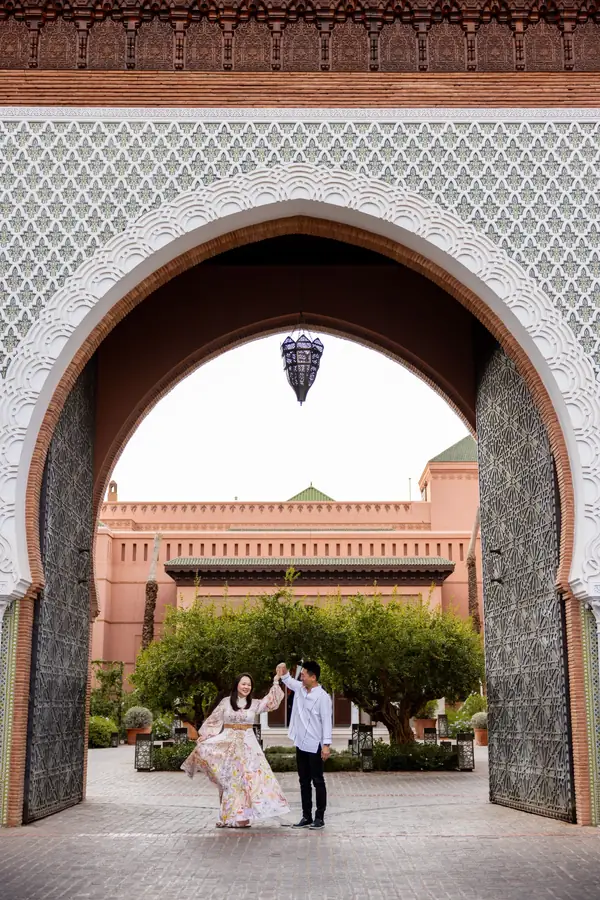 Couple dancing beneath a monumental Moroccan gate with a palace facade behind - wedding photographer Marrakech