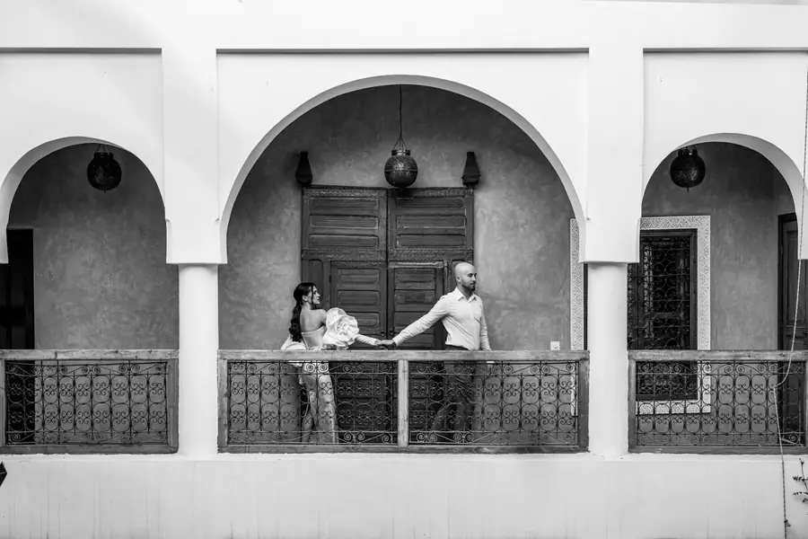 Black and white portrait of a couple on a riad balcony framed by white Moorish arches - riad wedding Marrakech